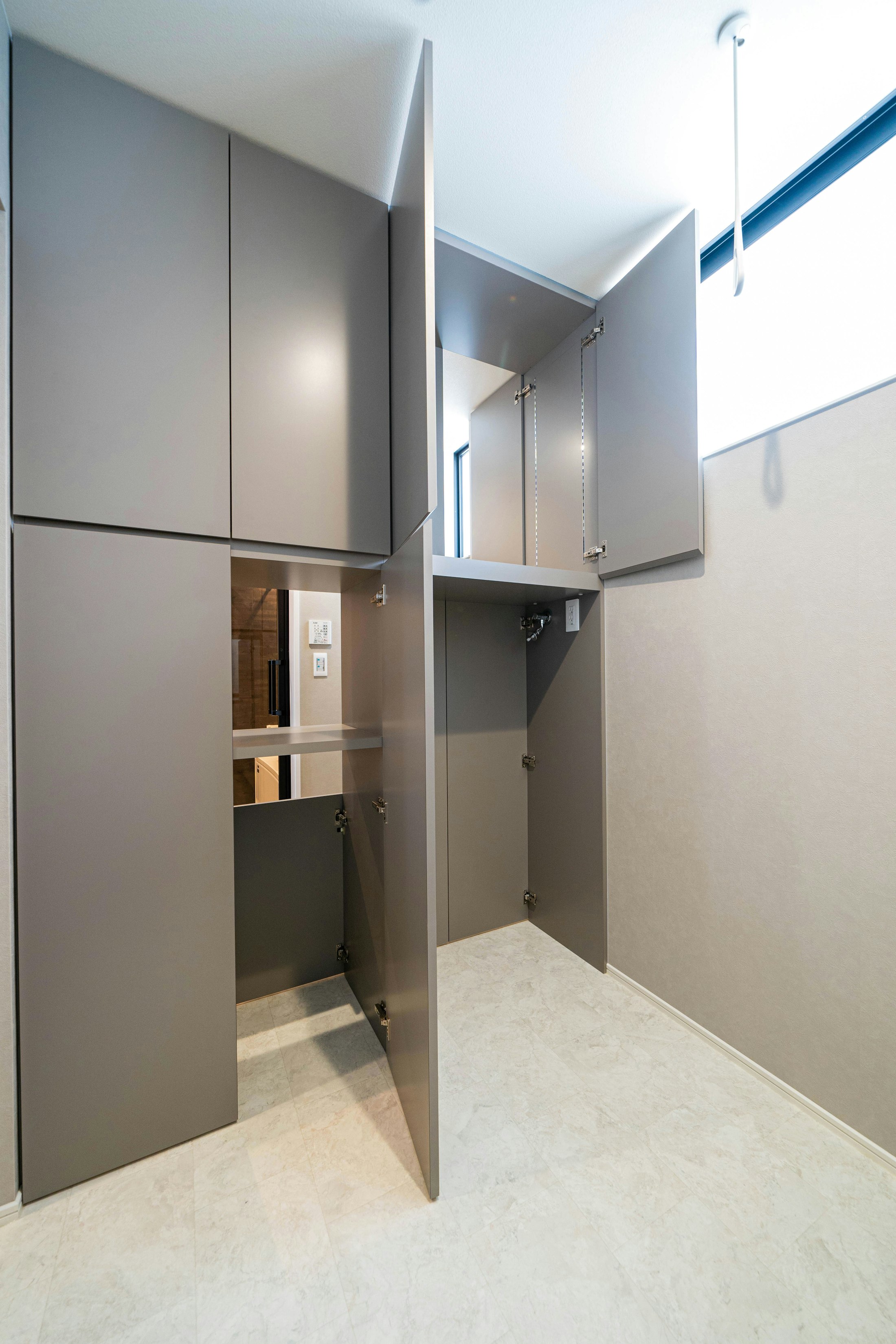脱衣室と洗濯機のあるサンルームの間には、両側から出し入れできる収納を設置