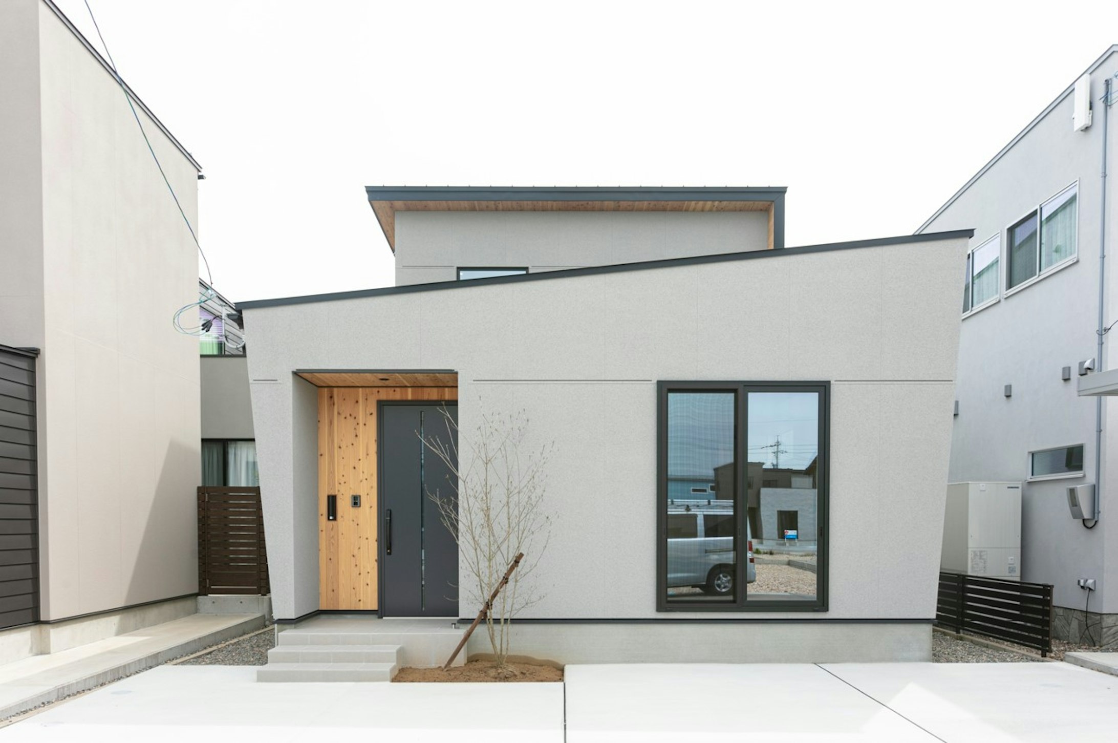 グレーの吹付材のアクセントが素材感を感じさせる上質なデザイン住宅